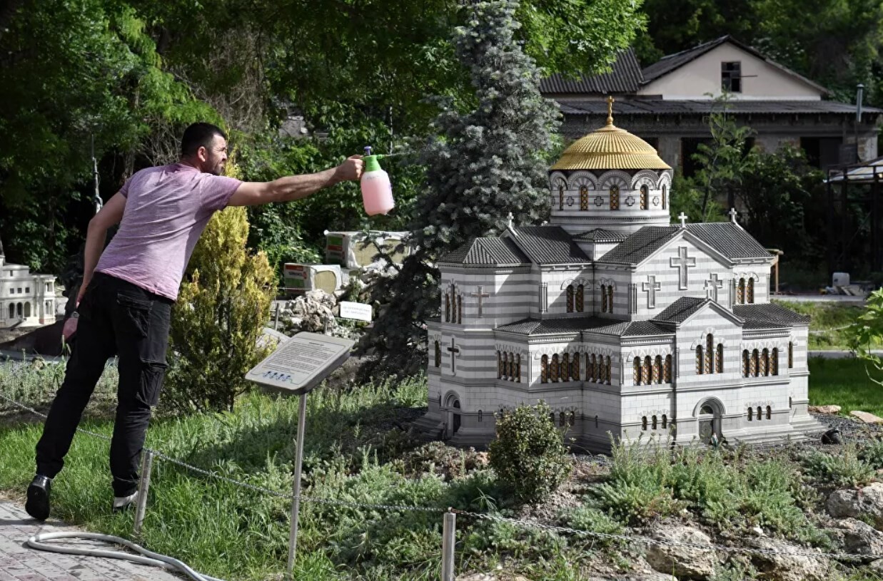 Người đàn ông đứng bên mô hình Nhà thờ Vladimir ở Khersones tại công viên Tiểu Crưm trong lòng bàn tay, ở thành phố Bakhchisarai